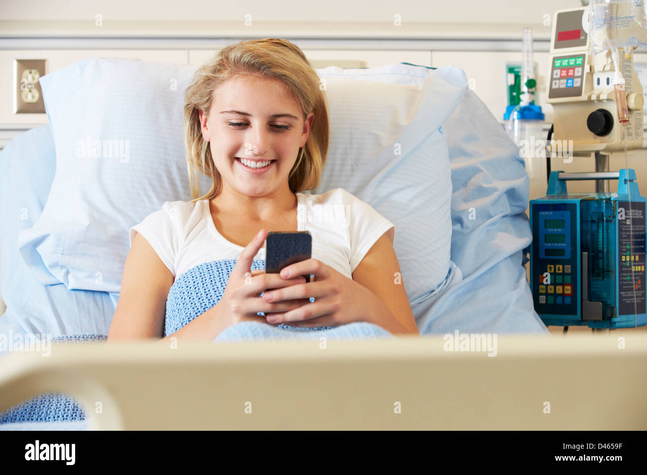 Teenager Patientin mit Handy im Krankenhausbett Stockfoto
