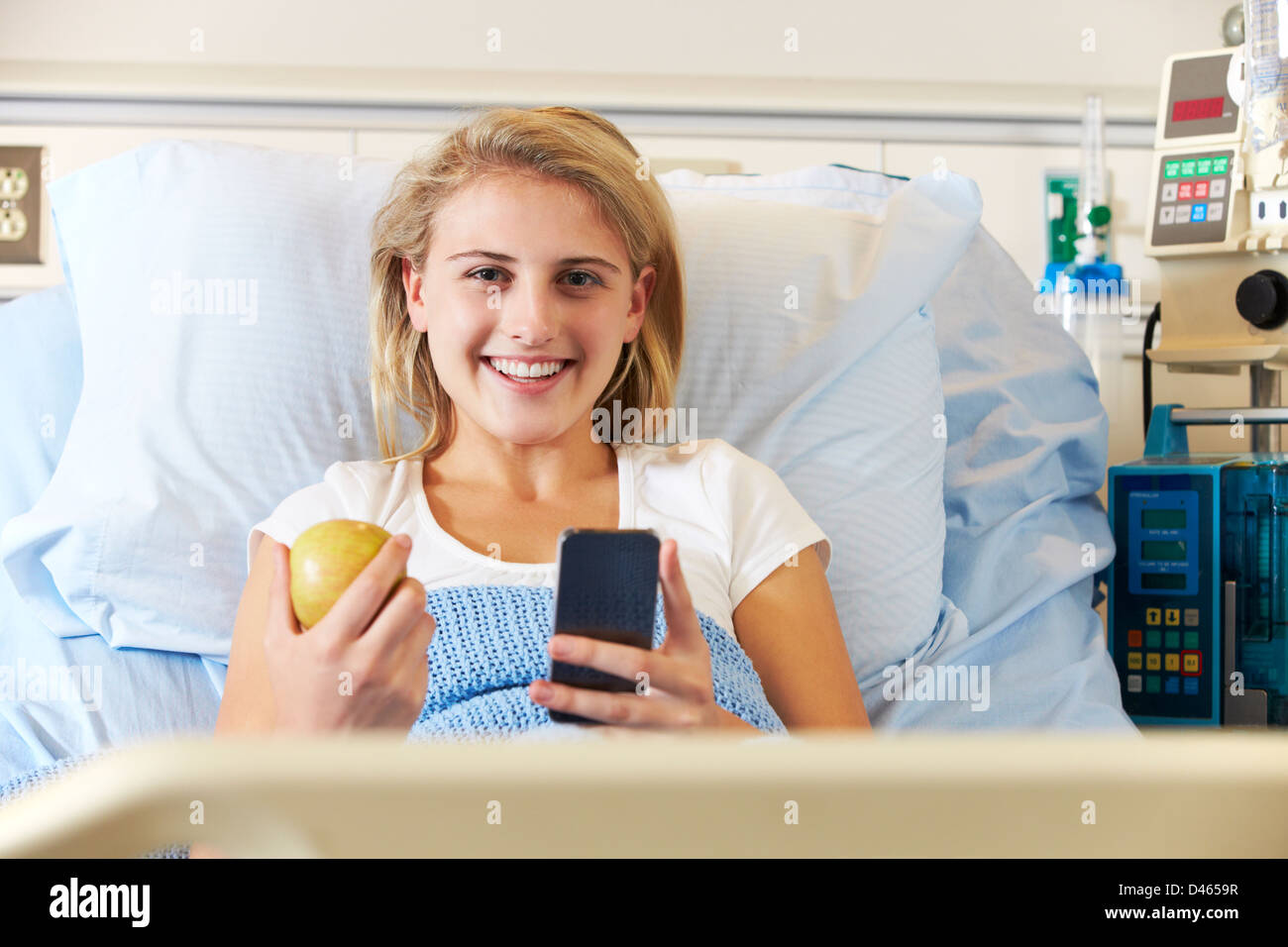 Teenager Patientin mit Handy im Krankenhausbett Stockfoto