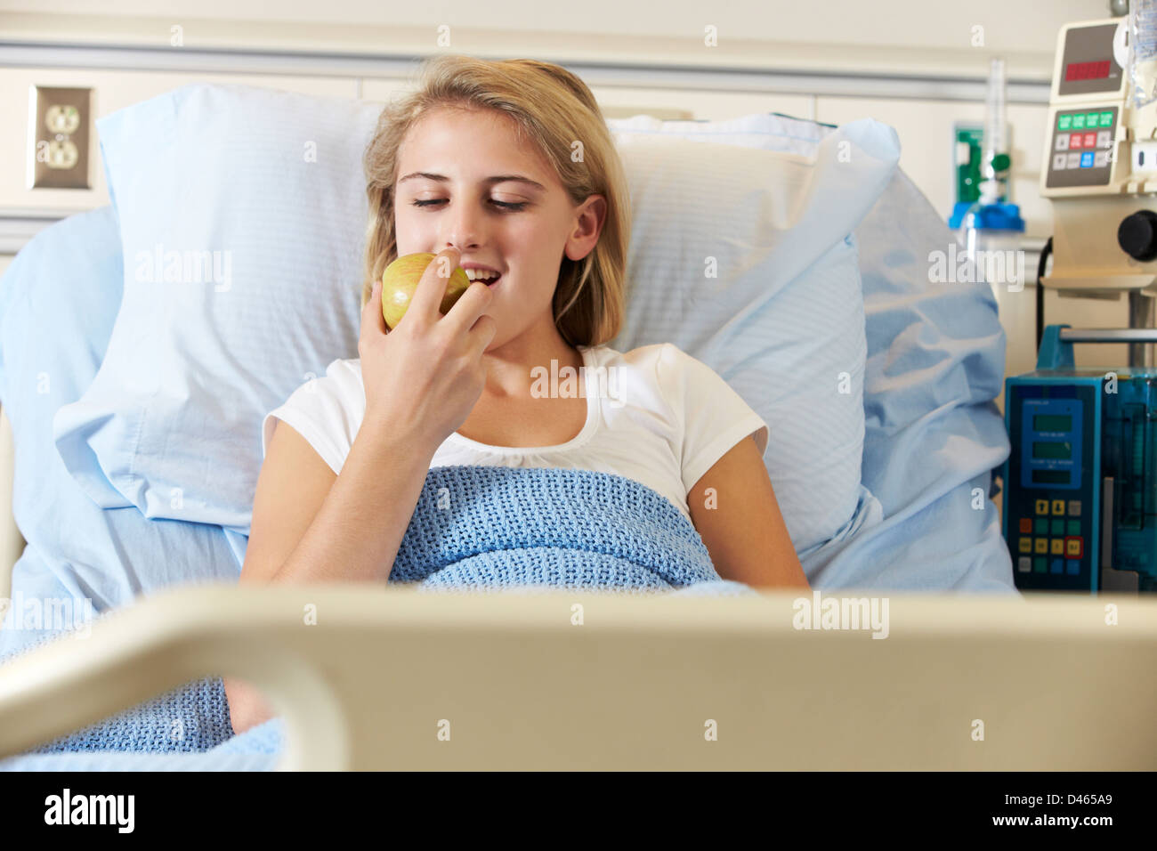 Teenager weibliche Patienten Essen Apfel im Krankenhausbett Stockfoto