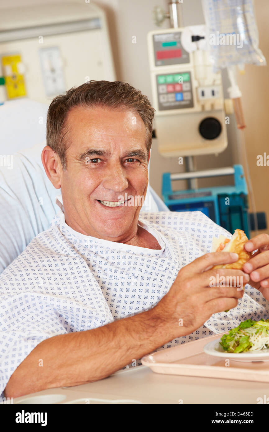 Männliche Patienten genießen Mahlzeit im Krankenhausbett Stockfoto