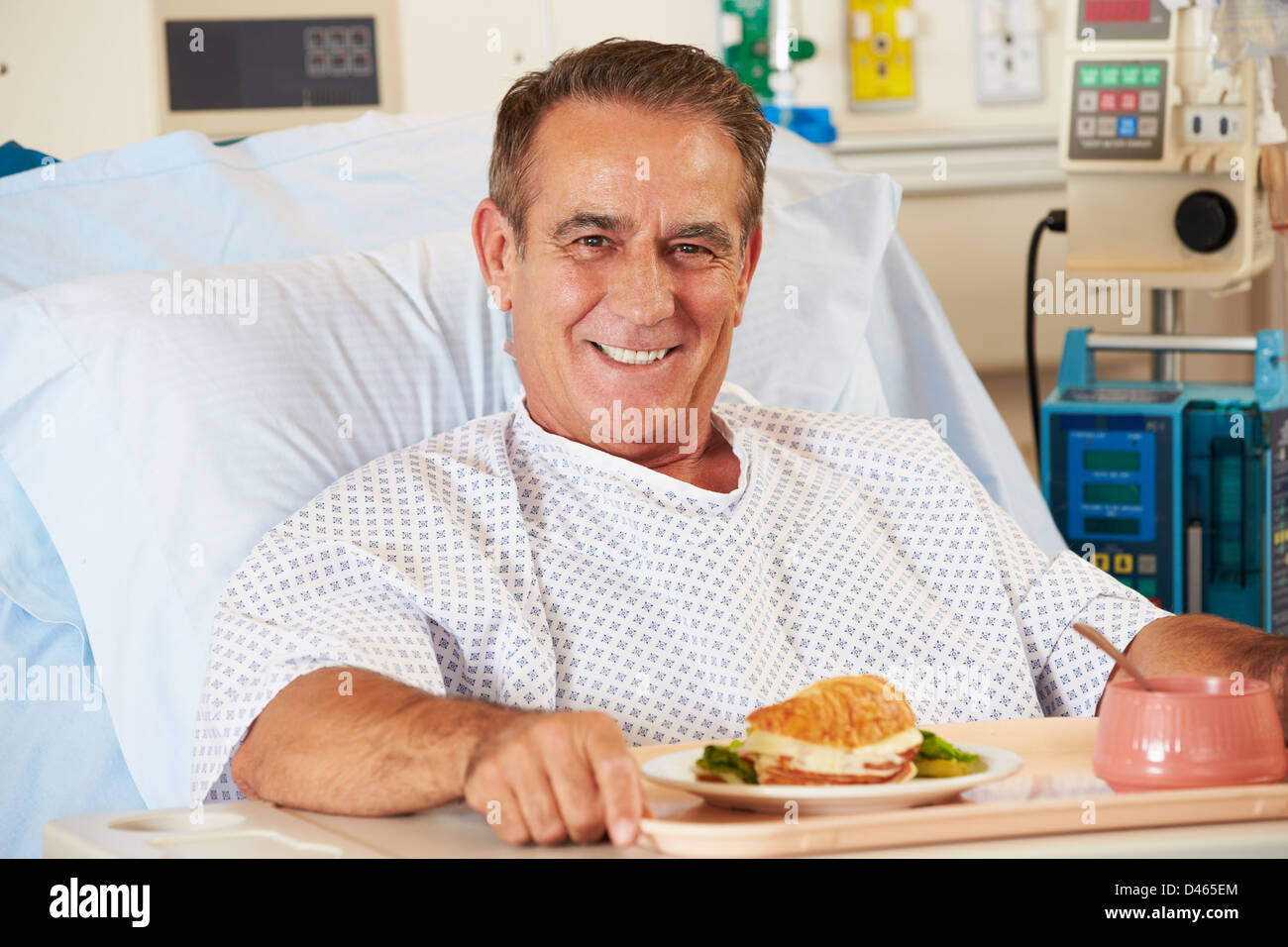 Männliche Patienten genießen Mahlzeit im Krankenhausbett Stockfoto