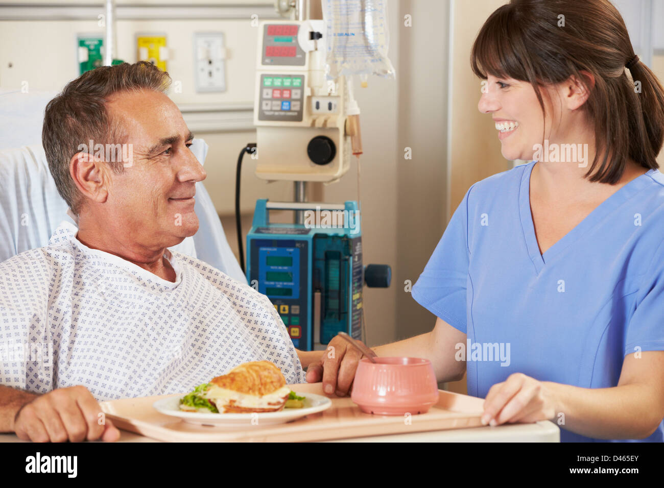 Patienten, die Mahlzeit serviert im Krankenhausbett von Krankenschwester Stockfoto