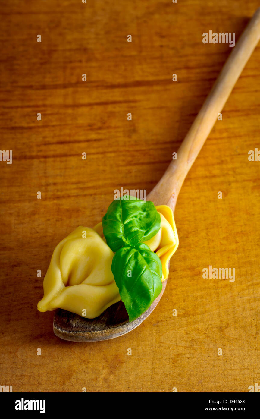 Hausgemachte Tortellini und Basilikum auf einem Holzlöffel Stockfoto