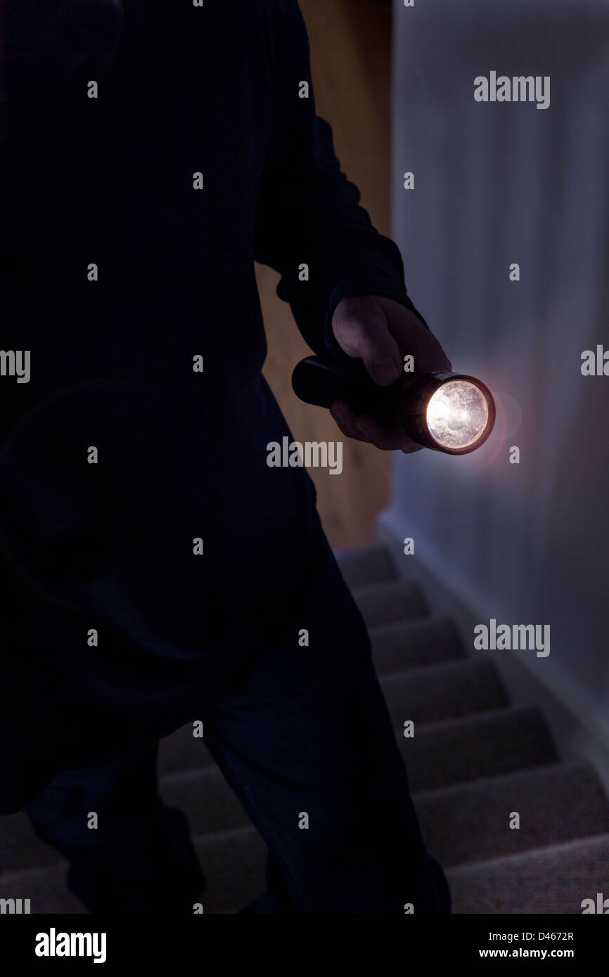 Schattenhafte männlichen Eindringling hält eine Taschenlampe oder Blitzlicht Stockfoto