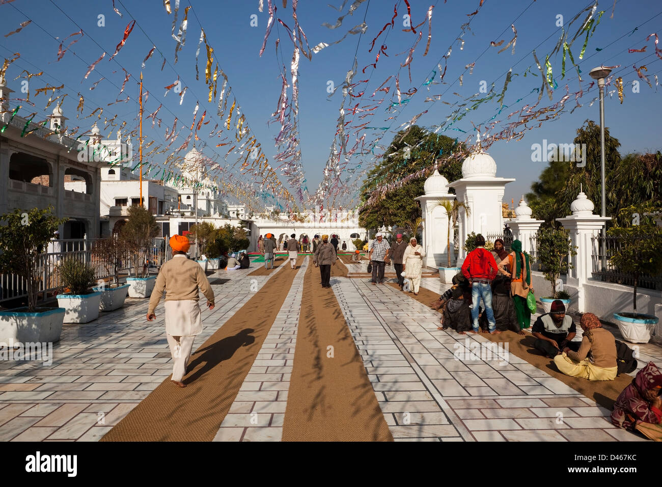 Bunte Eingang zum Goldenen Tempel in Amritsar, Punjab mit weißem Marmor Gebäude Menschen und Lametta unter blauem Himmel Stockfoto