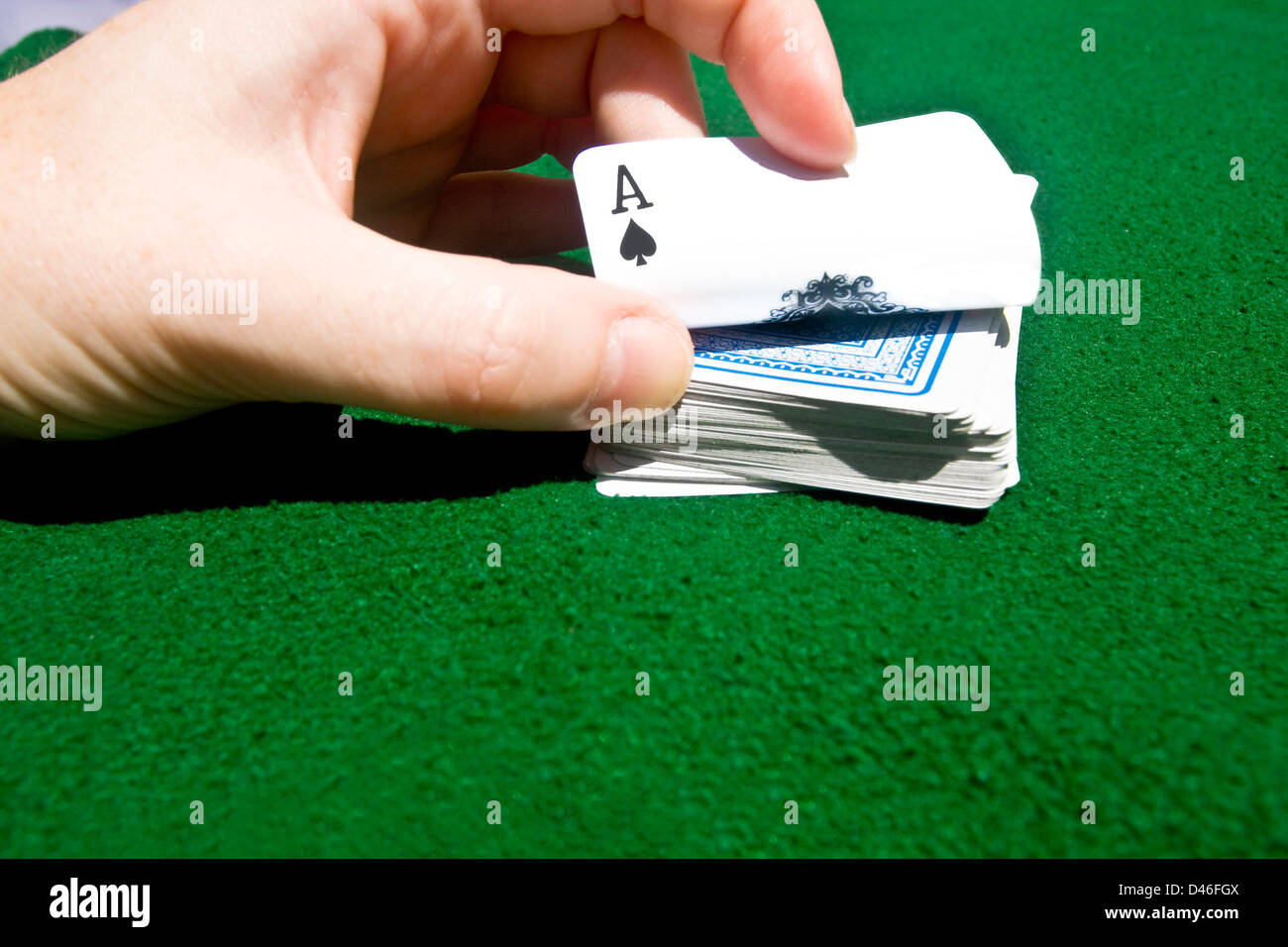 Ein Händler schleicht sich die nächste Karte umgehen zeigt die Ace of Spades. Stockfoto