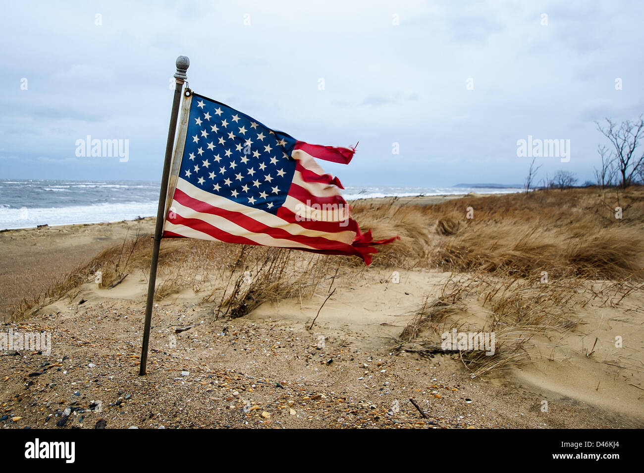 Union Beach, NJ, USA, 6. März 2013. Eine amerikanische Flagge ist von 50 Meilen pro Stunde Böen gepeitscht.  Union Strand ist derzeit selbst Winter Sturm Saturn Aussteifung für die bereits enthaltenen Deichen bedroht.  Ein Großteil der Schäden im Oktober noch nicht repariert werden. Stockfoto