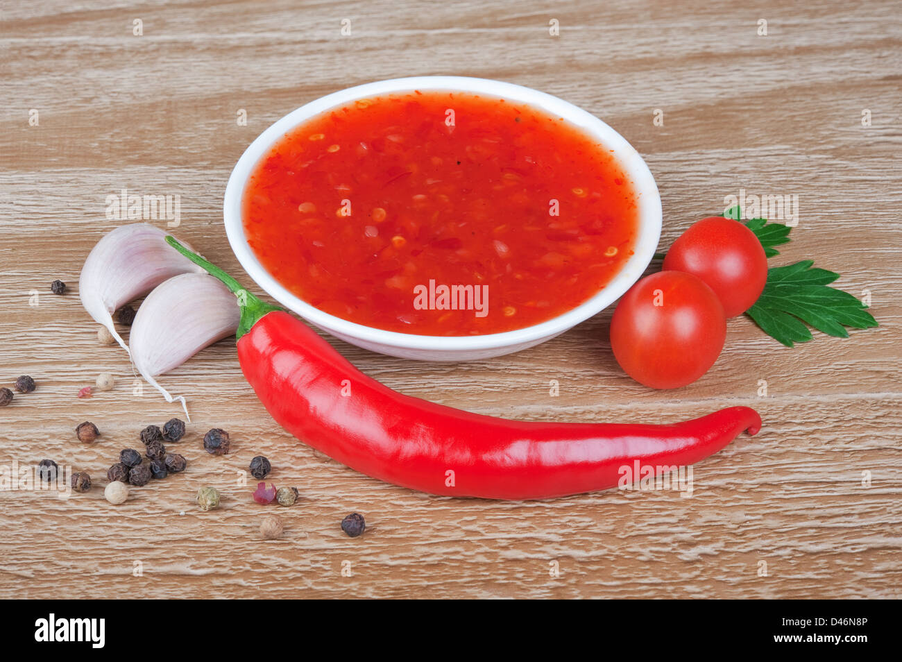 Red hot Chilisoße über hölzerne Hintergrund Stockfoto