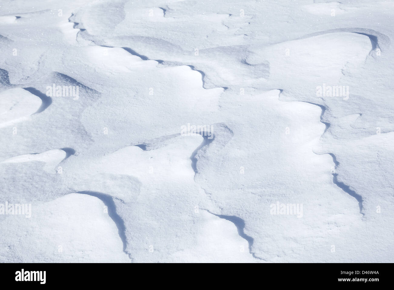 Hintergrundtextur von hügeligen Schneewehe mit schön geschwungenen Schatten Stockfoto