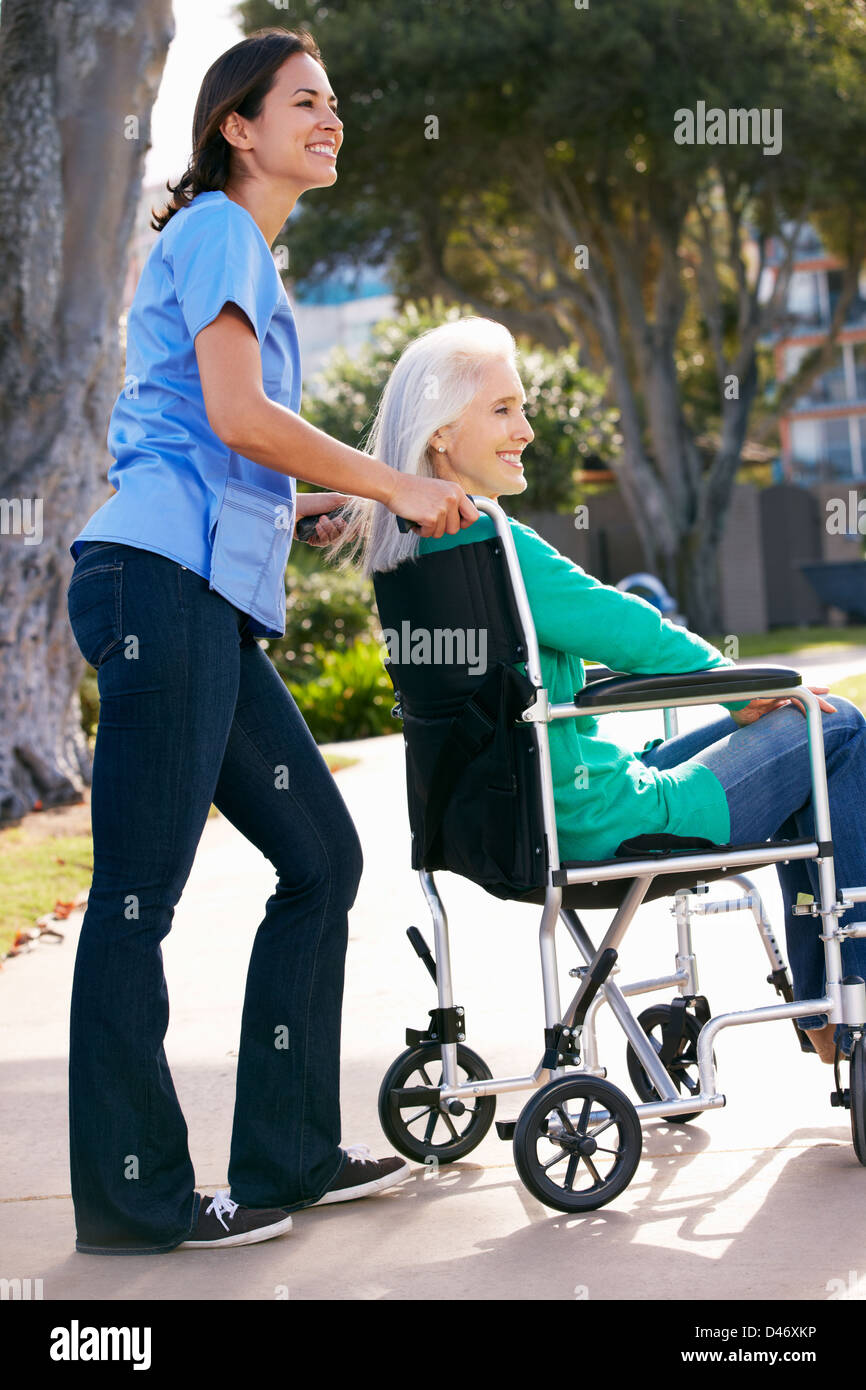 Pflegeperson Senior Frau im Rollstuhl schieben Stockfoto
