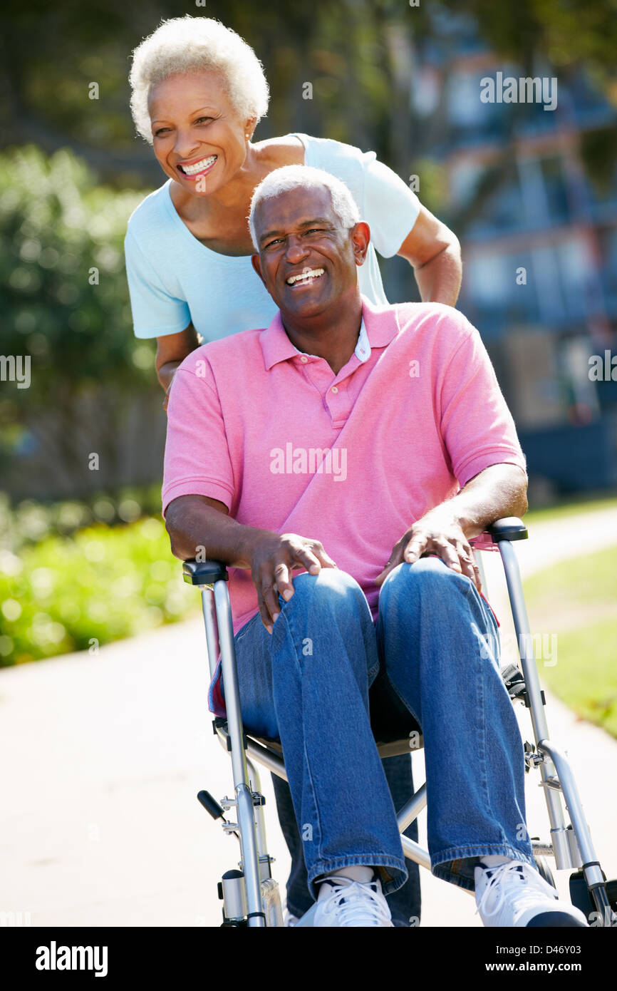 Ältere Frau, die Mann im Rollstuhl schieben Stockfoto