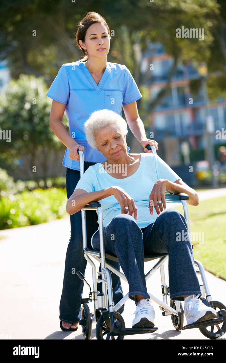 Pflegeperson unglücklich Senior Frau im Rollstuhl schieben Stockfoto