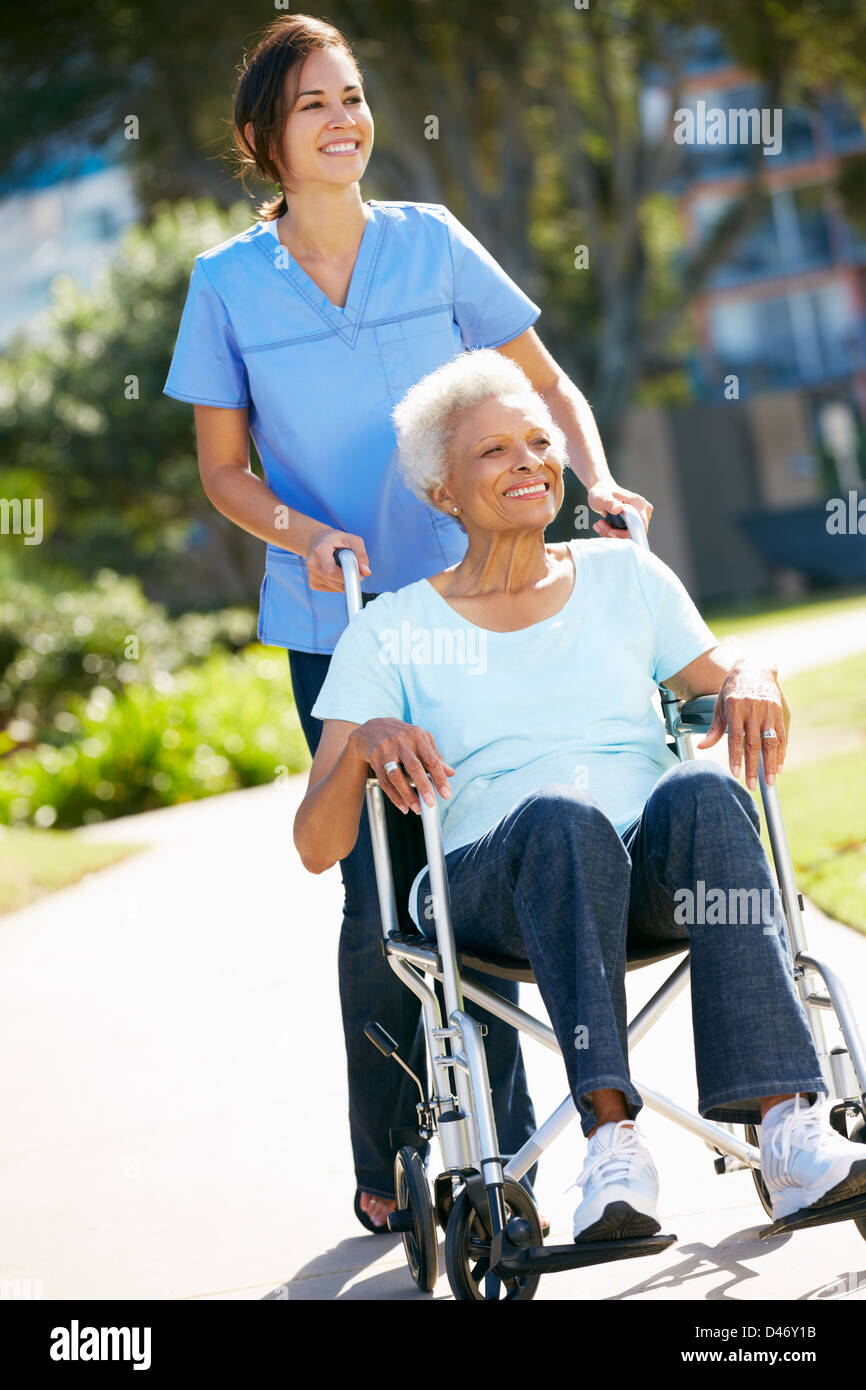 Pflegeperson Senior Frau im Rollstuhl schieben Stockfoto