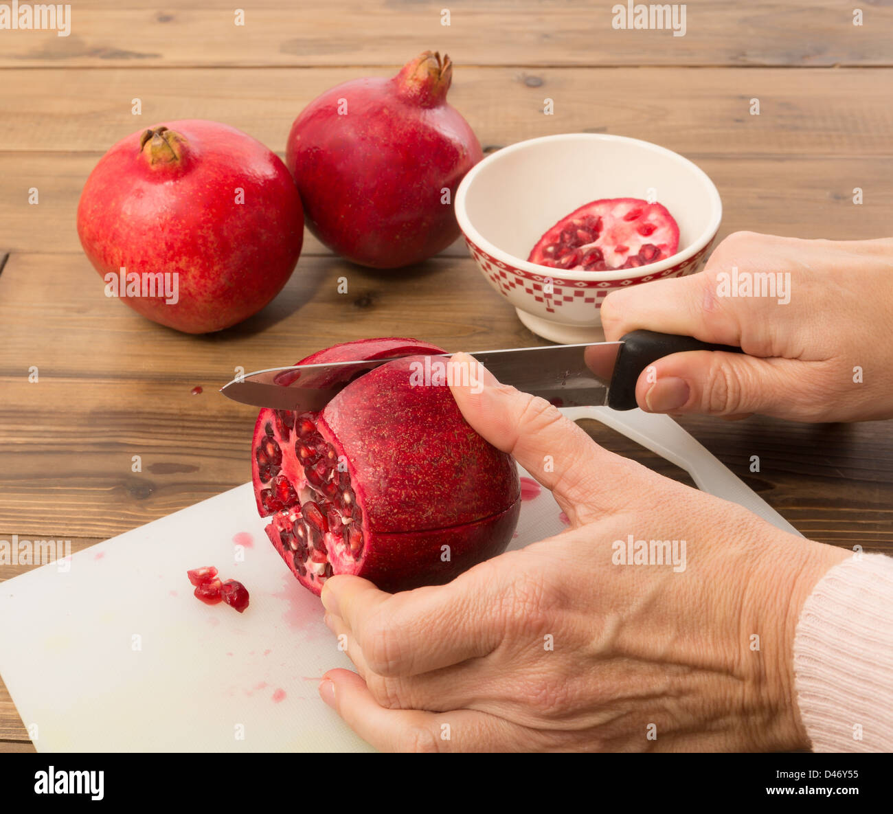 Hände, schneiden einen Granatapfel in vier Viertel Stockfoto