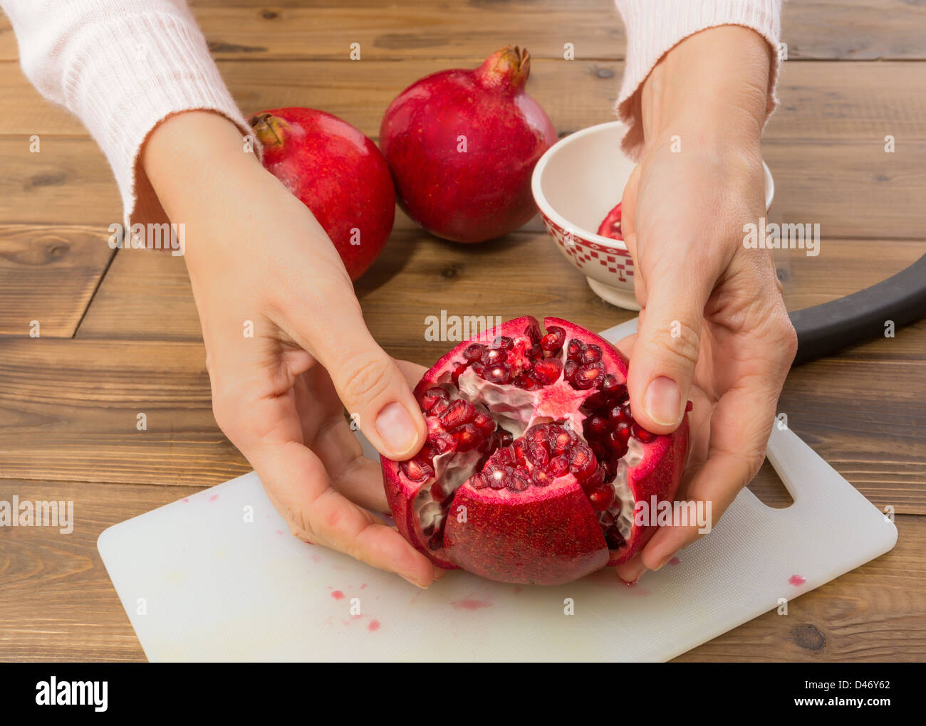 Hand einen Granatapfel öffnen und zeigen die Samen Stockfoto