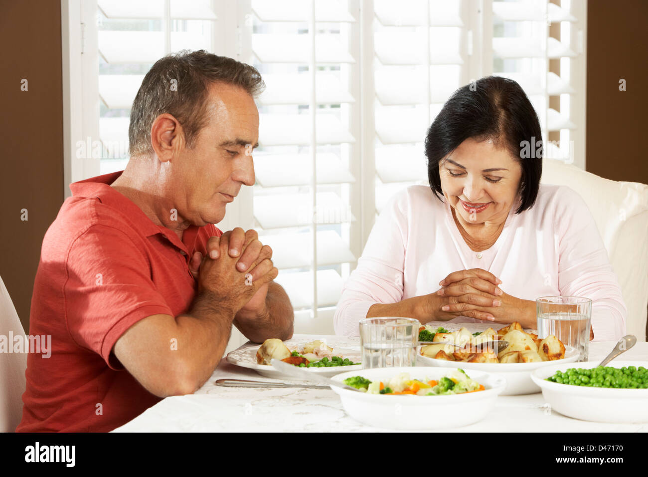 Senior paar sagen Gnade vor der Mahlzeit zu Hause Stockfoto