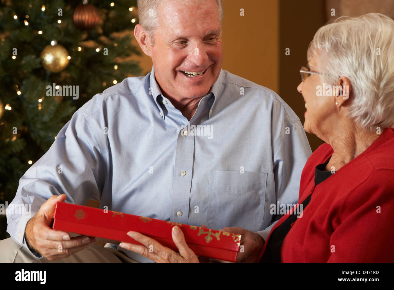 Älteres Paar Austausch von Geschenken vor Weihnachtsbaum Stockfoto