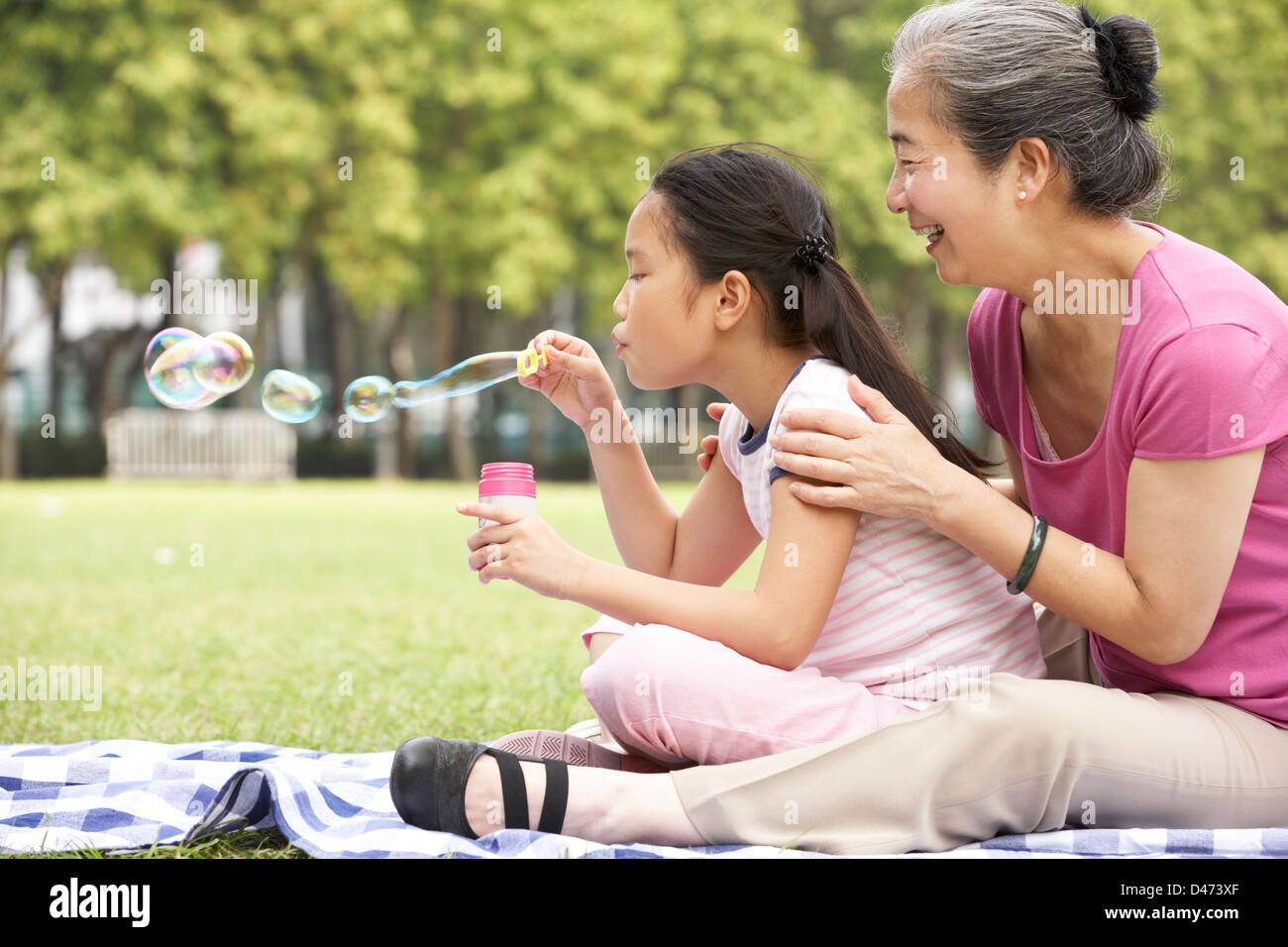 Chinesische Großmutter mit Enkelin im Park Seifenblasen Stockfoto