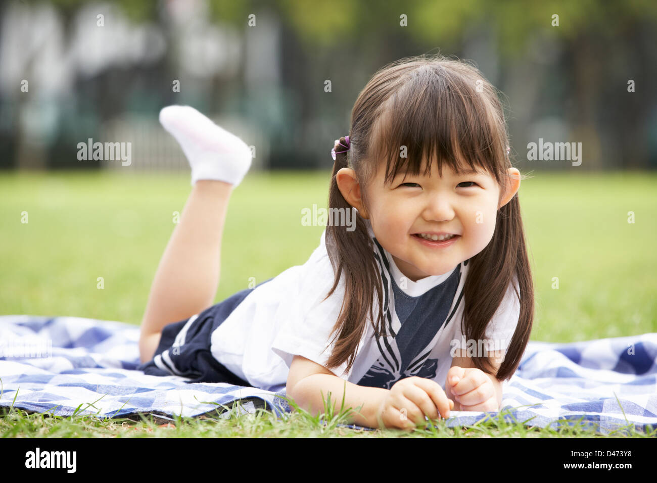 Junge Chinesin liegend auf einer Decke im Park Stockfoto