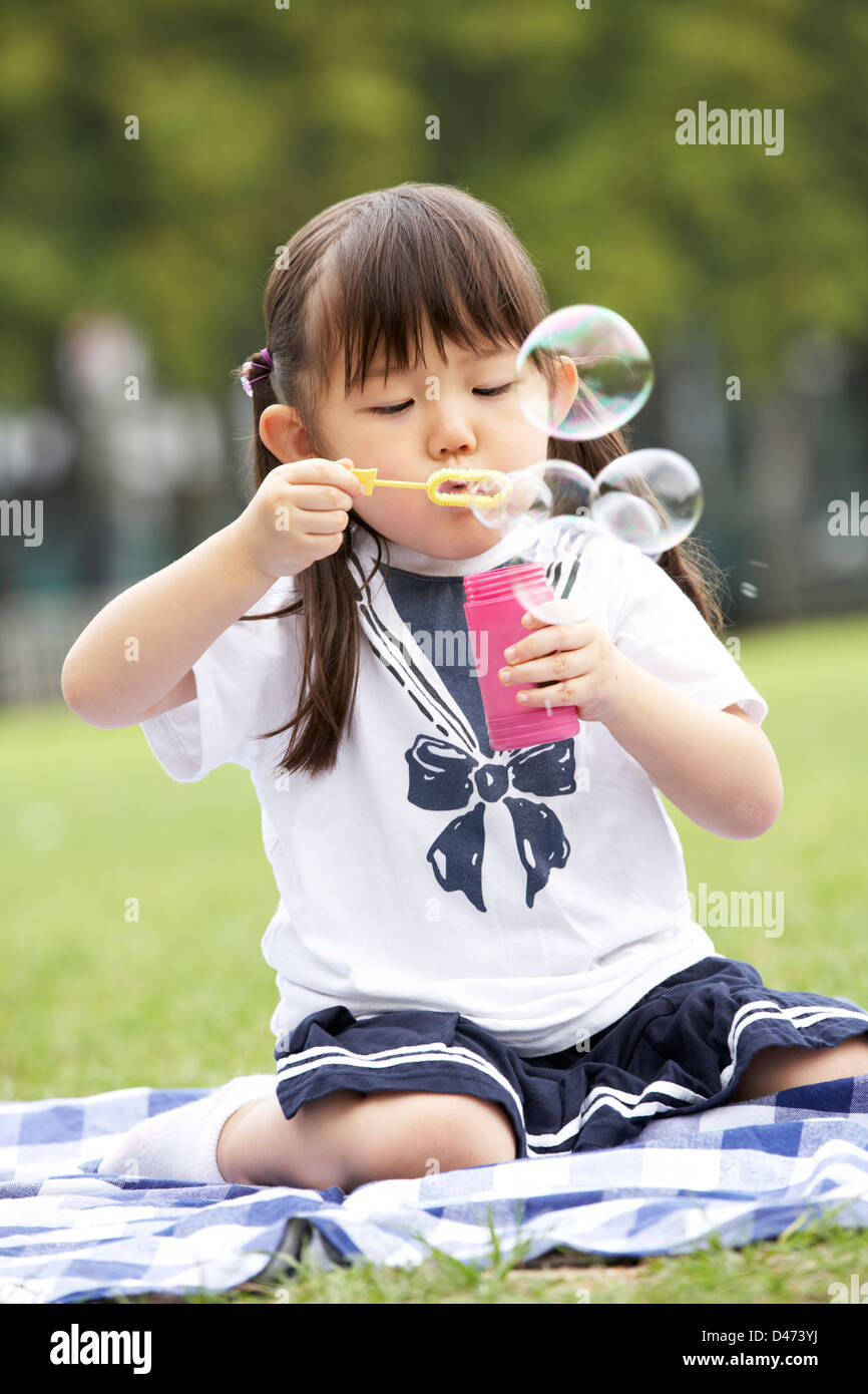 Junge Chinesin im Park Seifenblasen Stockfoto