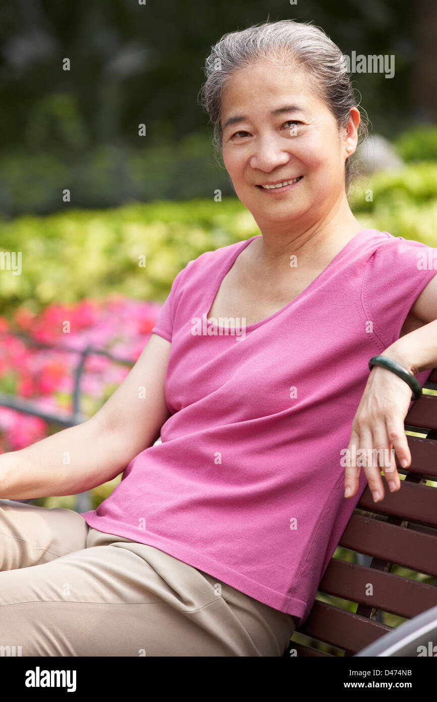 Entspannen Sie sich auf der Parkbank Senior Chinesin Stockfoto