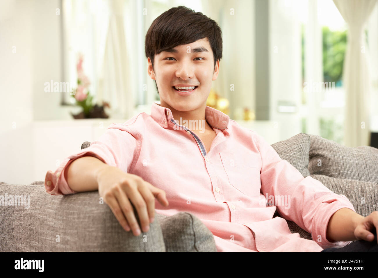 Junge chinesische Mann auf Sofa zu Hause entspannen Stockfoto