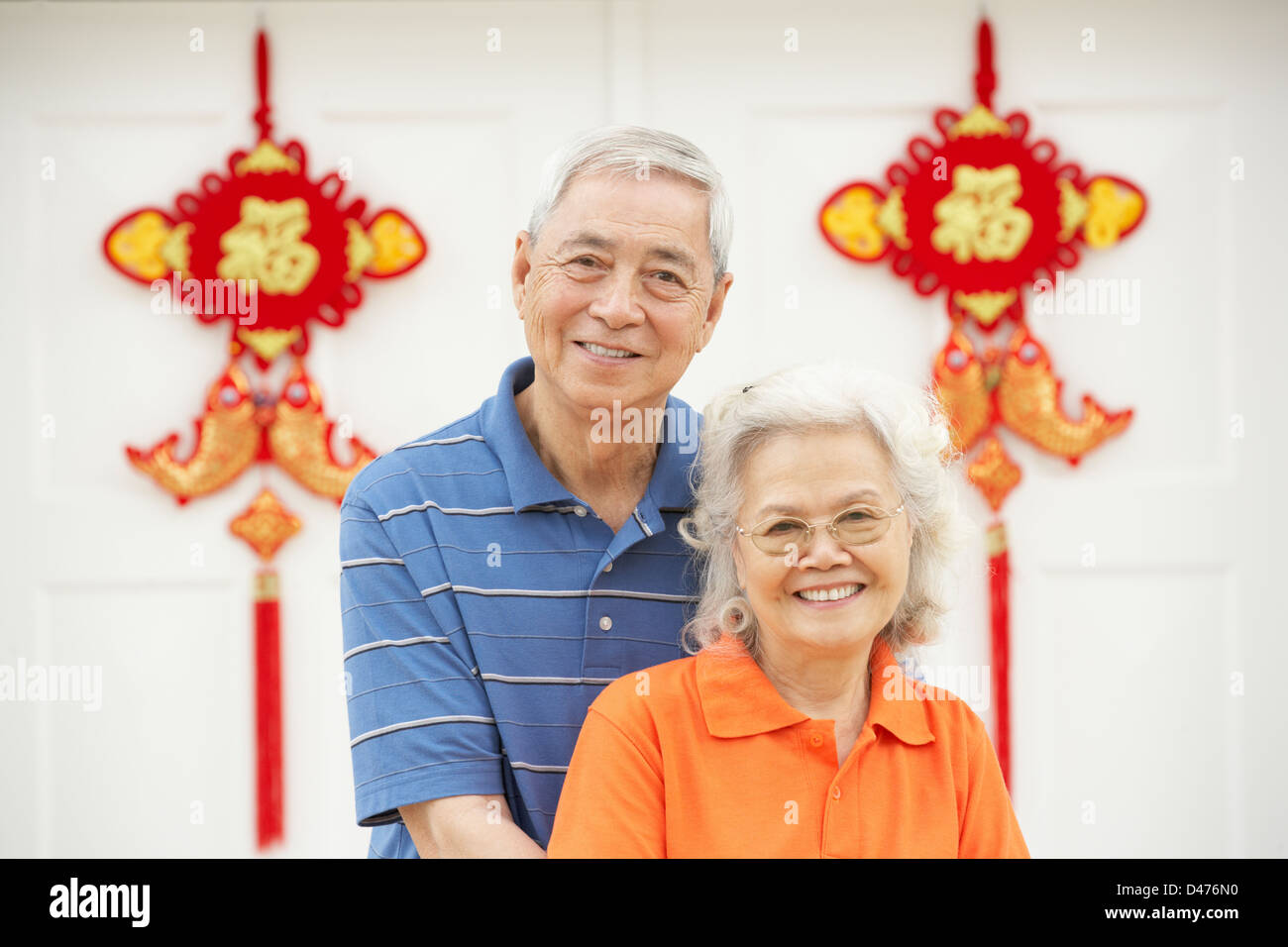 Senior Chinesisch paar außen Haus verziert mit einladenden Feng Shui Banner Stockfoto