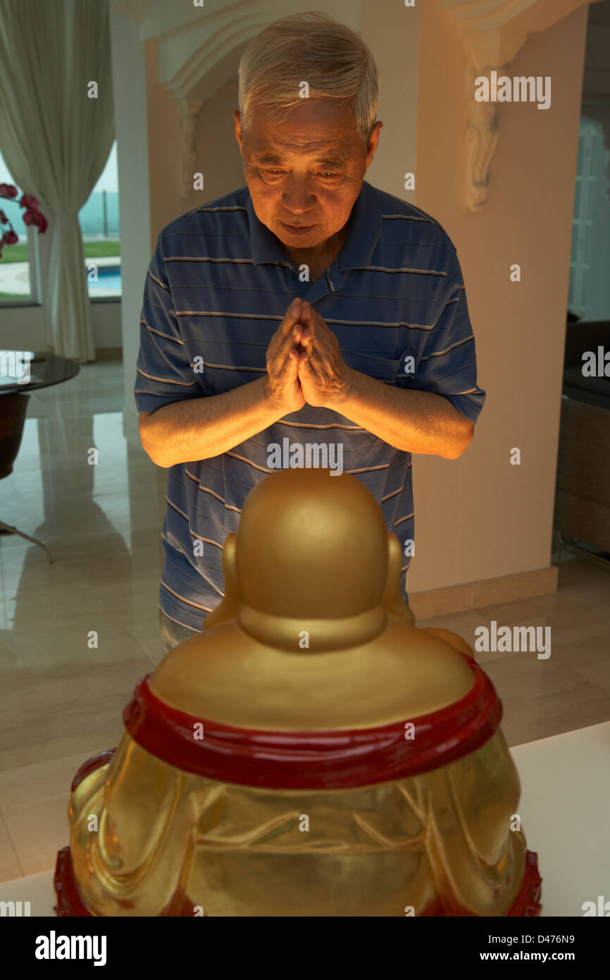 Hochrangige chinesische Mann beten zu Buddha-Statue zu Hause Stockfoto