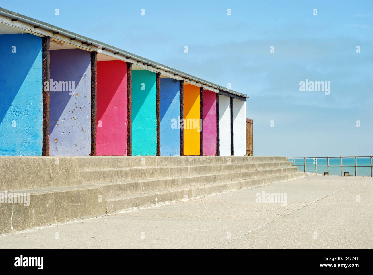 alte bunte Strandhütten in einer Reihe mit blauen Himmel und Wolken Stockfoto