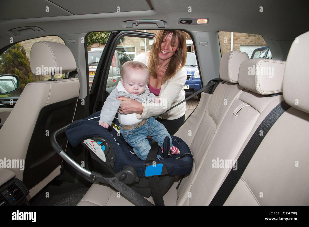 Reife Mutter, Baby Boy in seinem Autositz montiert und mit einem Gurt im hinteren Teil dieses Fahrzeug gesichert. Ältere Mutter Stockfoto