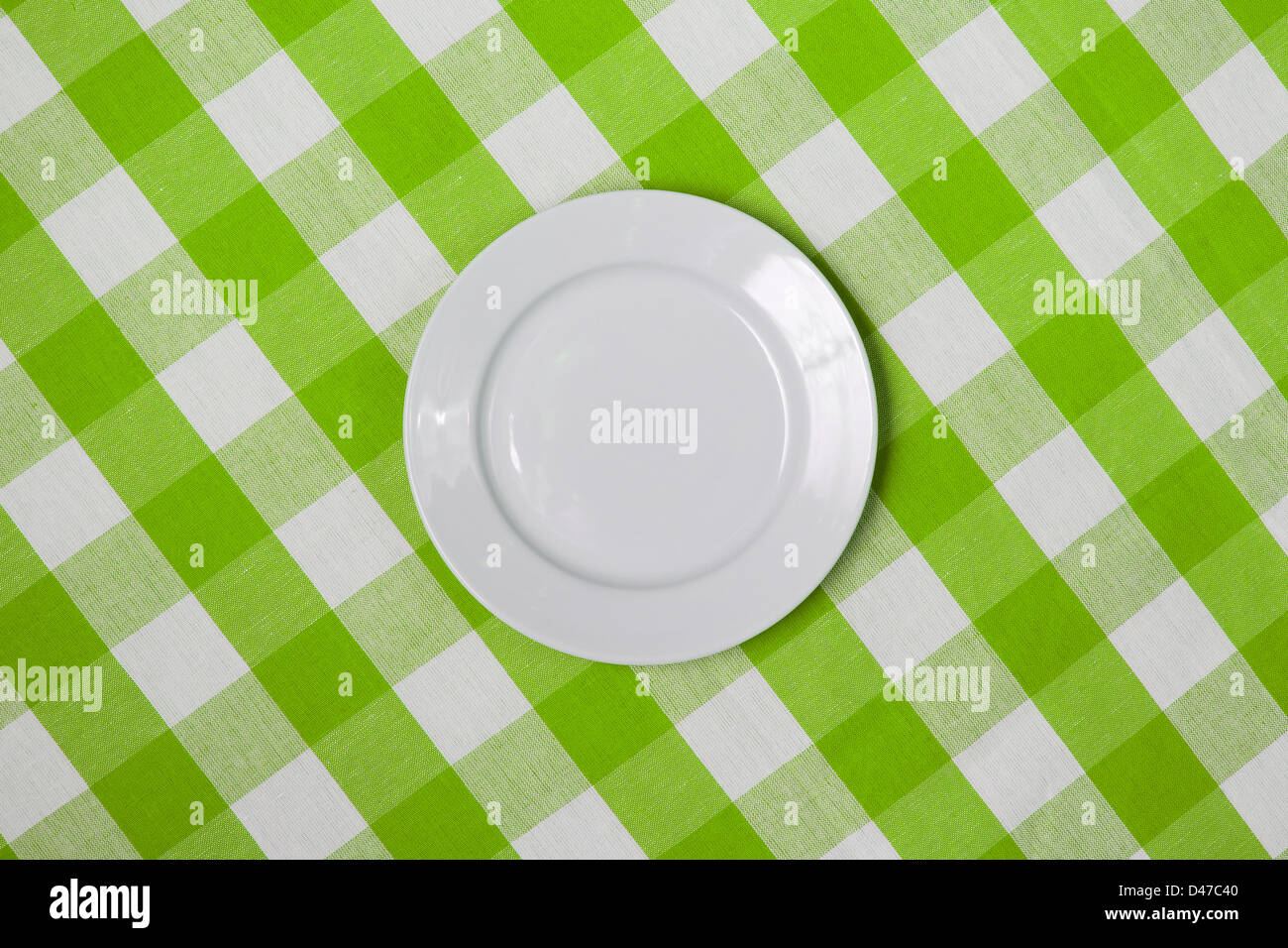 Weiße runde Platte auf grüne aufgegebenes Tischdecke Stockfoto