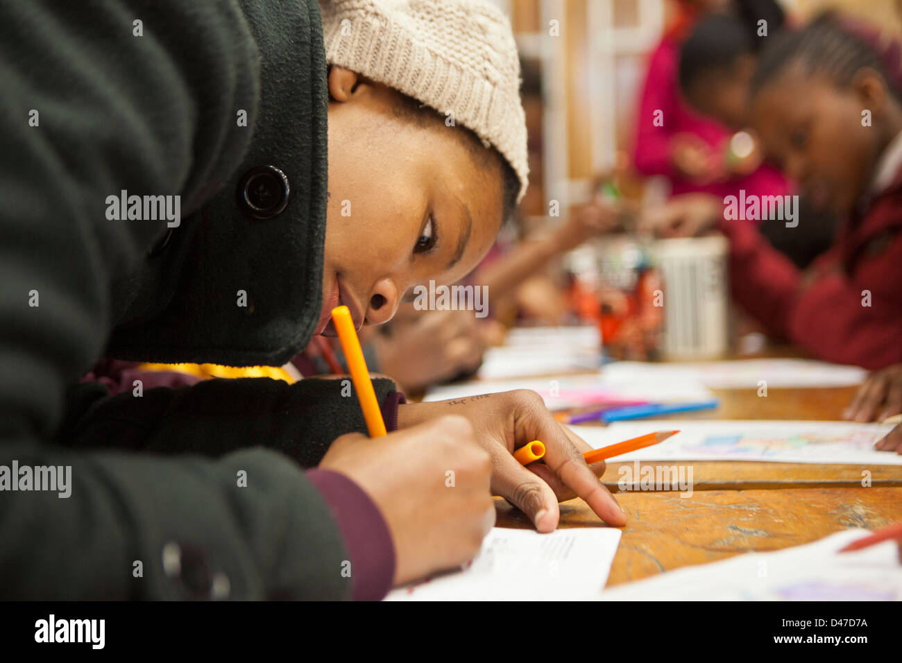 Afrikanische Grundschulkinder Färbung in Karten von Afrika auf einem Schreibtisch in einem Klassenzimmer in Cape Town, Südafrika. Stockfoto