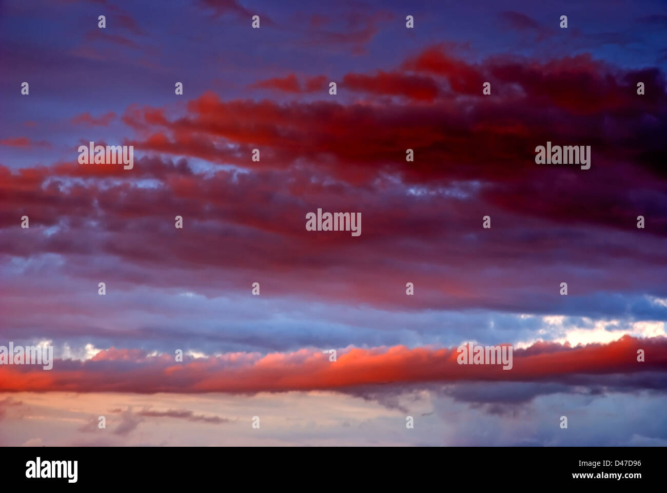 Wolken auf einem Sonnenuntergang sind von der Sonne in roter Farbe bemalt. Stockfoto