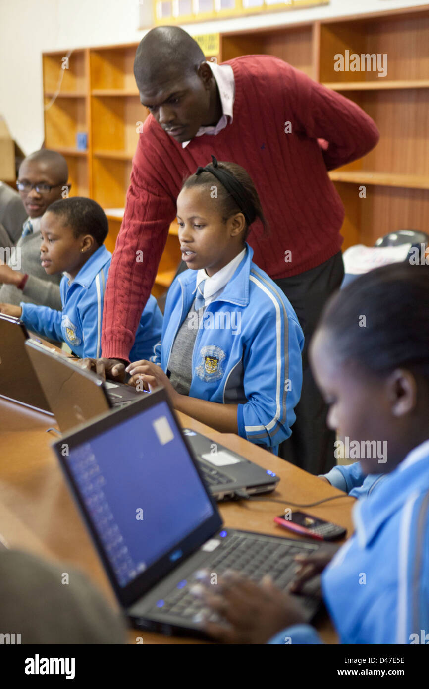 Lehrer hilft südafrikanischen Schulkinder auf Laptops während einer Computer-Förderklasse, Cape Town, Südafrika. Stockfoto