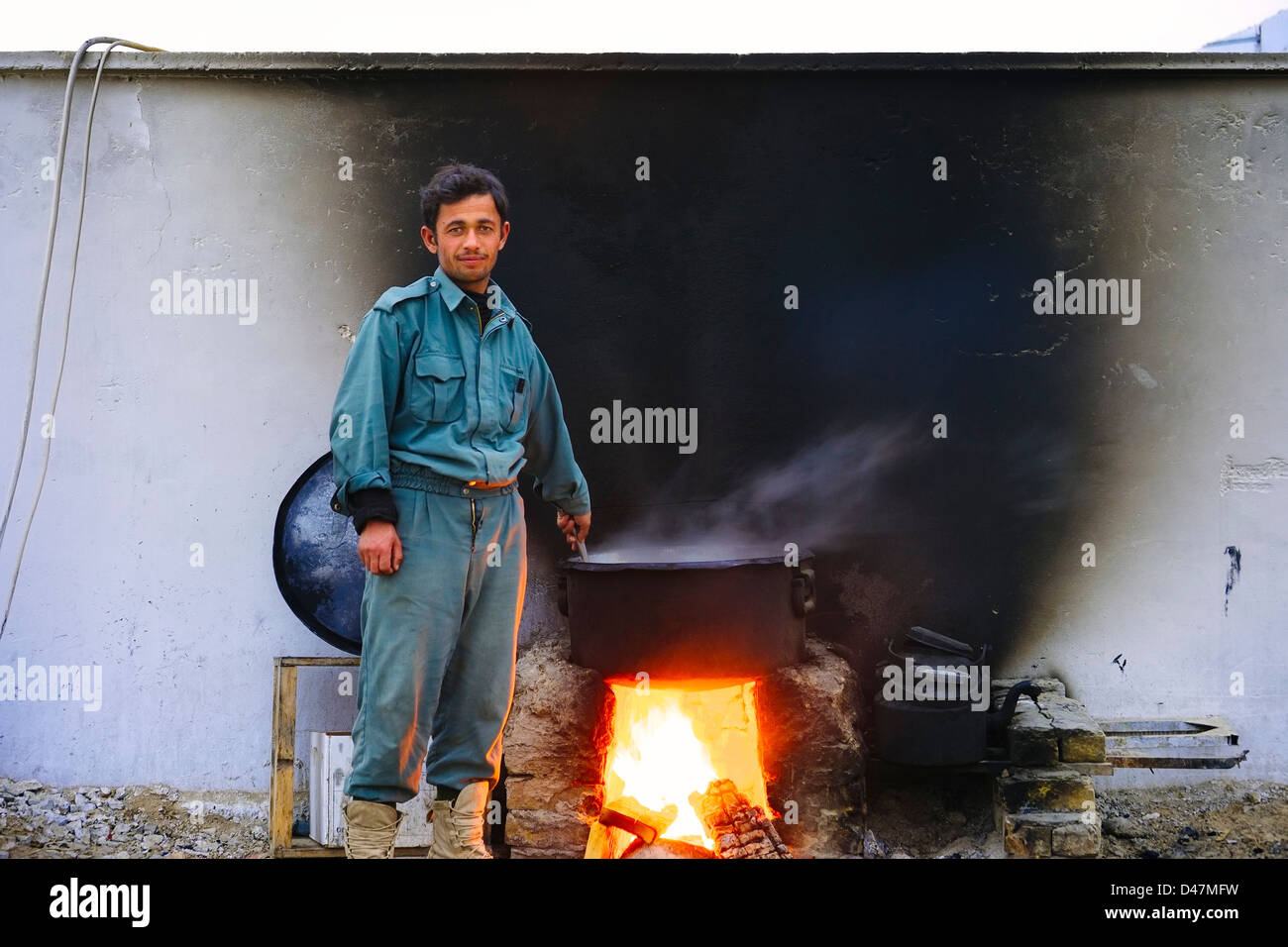 Kandahar, Afghanistan - 10. Januar 2011: Ein afghanischer Polizist kocht Abendessen für seine Mannschaft an einem kalten Winterabend. Stockfoto