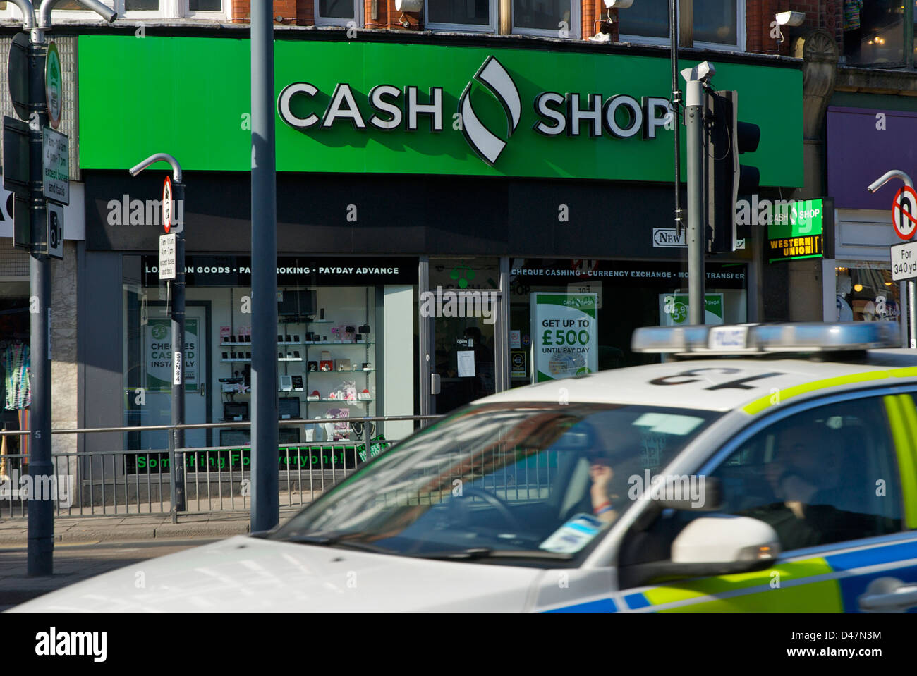 Polizeiauto vorbei an Cash-Shop in Leeds, West Yorkshire, England UK Stockfoto