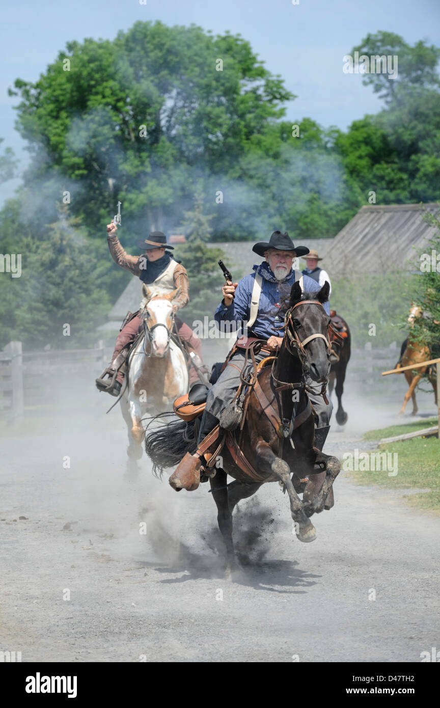 Cowboys reiten hart und schnell durch die Stadt mit sechs Guns blazing, Rowdy Männer Ärger mit viel Staub und Action zu machen. Stockfoto