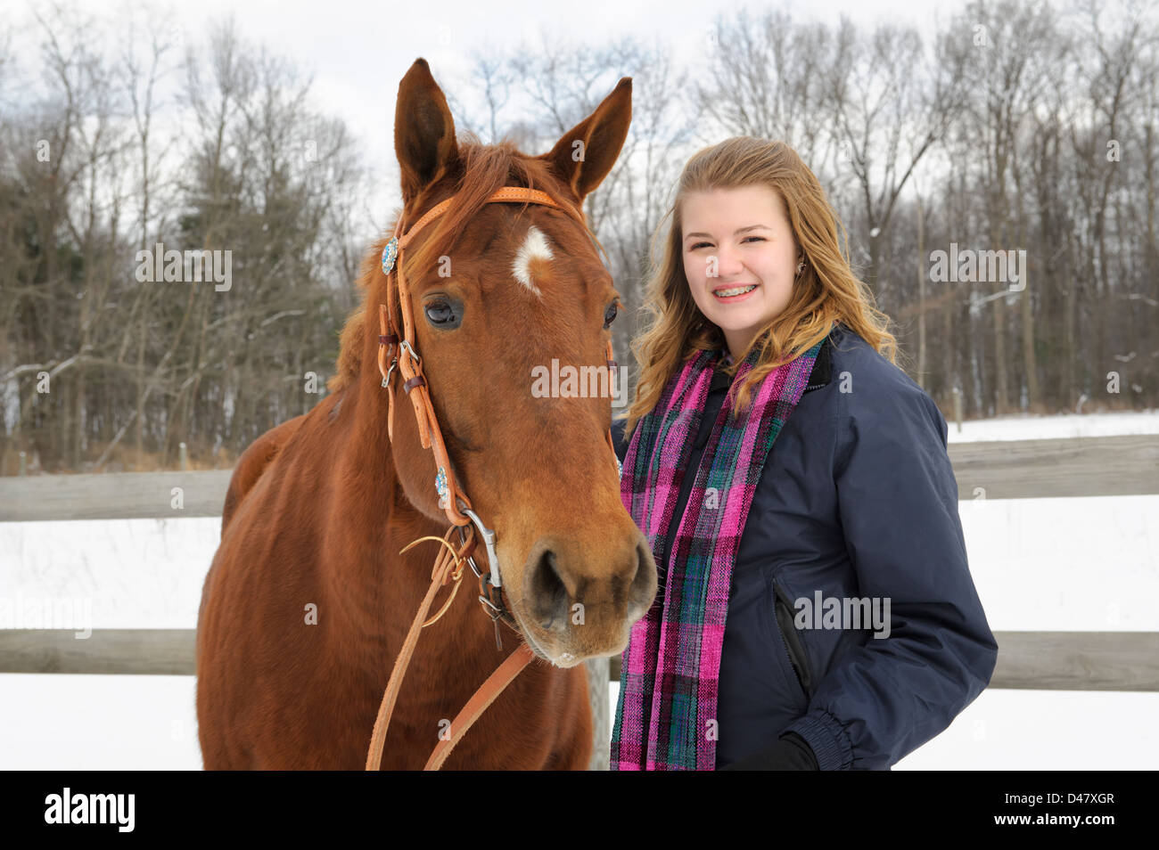 Junge Teenager-Mädchen im Freien mit ihrem Pferd im Winterschnee, blonden Haaren und schönen Schal. Stockfoto