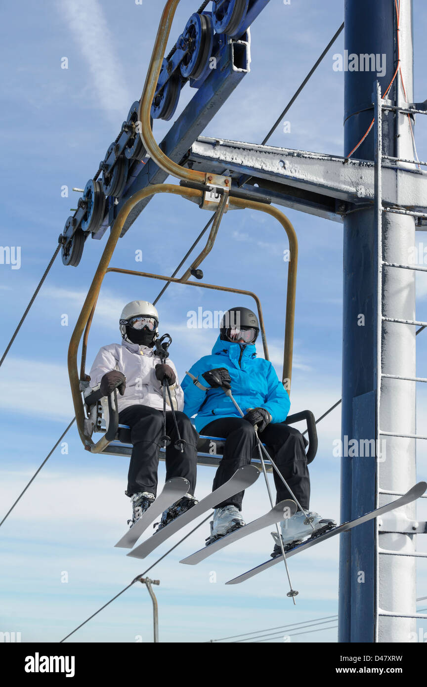 Zwei Skifahrer Skilift Stuhl in der Nähe Reiten, Mann und Frau mit Sonnenlicht und Schönwetter Himmelshintergrund, Textfreiraum. Stockfoto