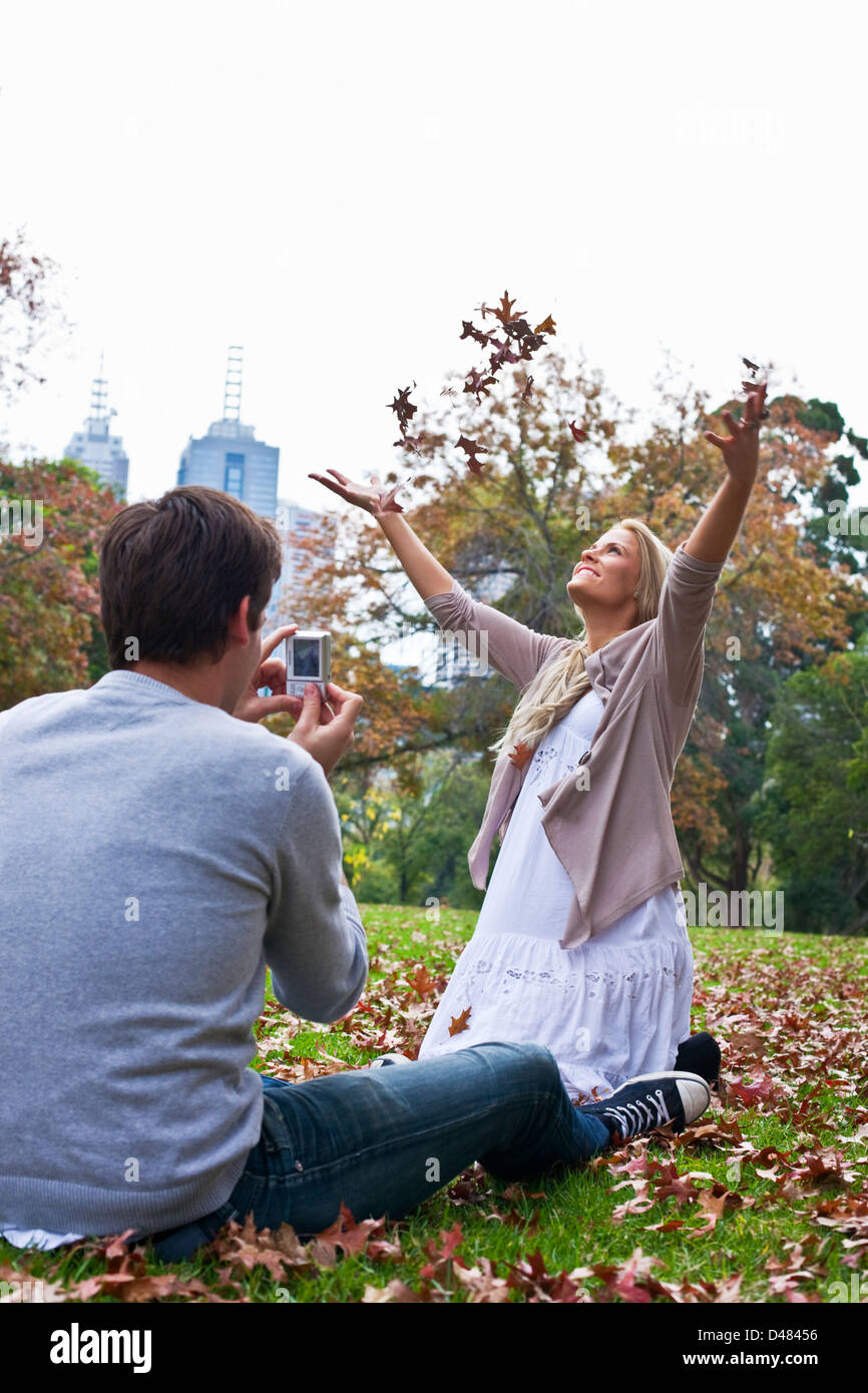 Junge Paare, die Spaß mit Herbstlaub im Park. Melbourne, Victoria, Australien Stockfoto