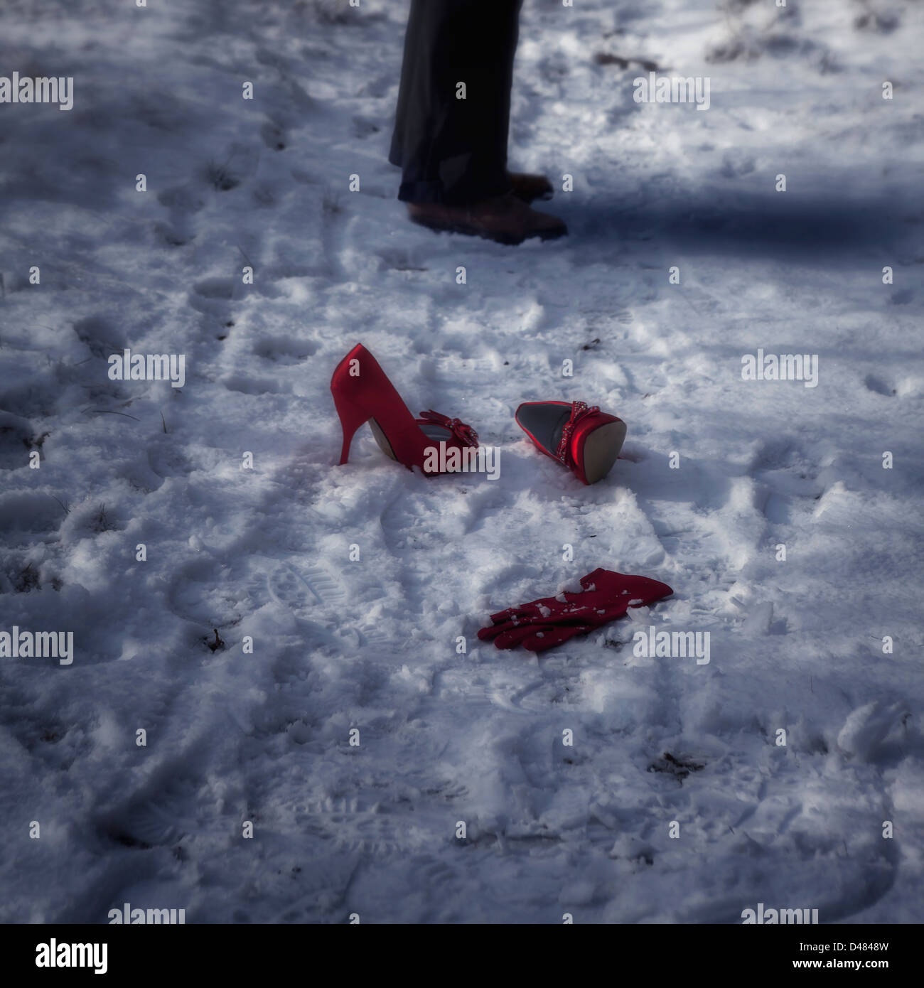 rote high Heels und ein Handschuh im Schnee, steht ein Mann neben Stockfoto