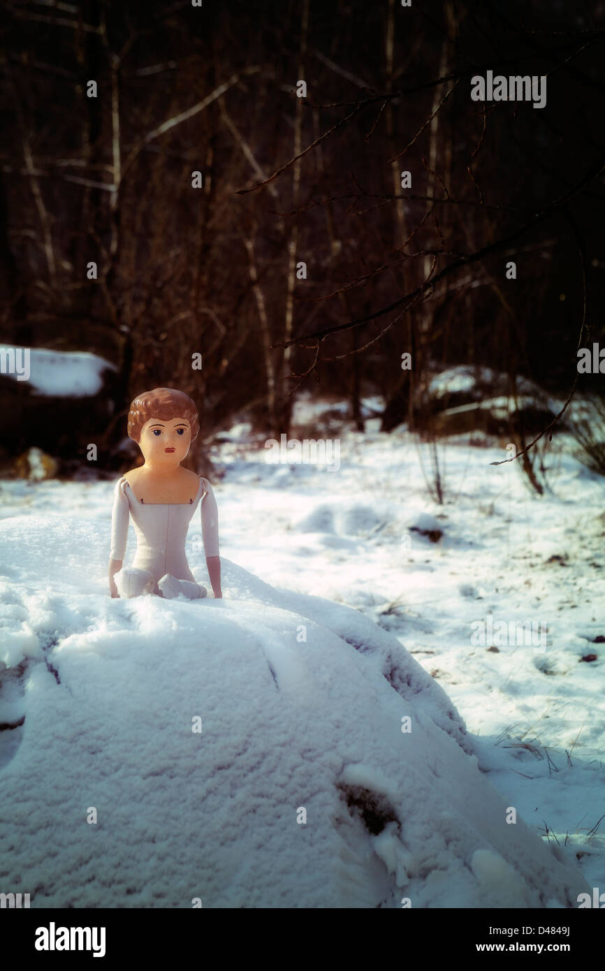 eine alte, Vintage Puppe sitzt im Schnee Stockfoto