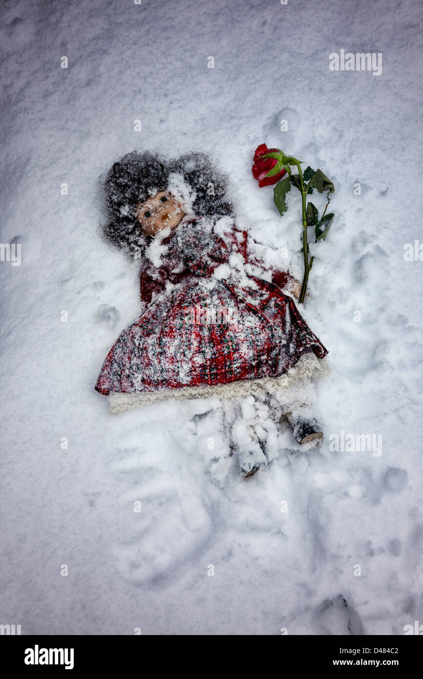 Puppe mit einer roten Rose im Schnee begraben Stockfoto