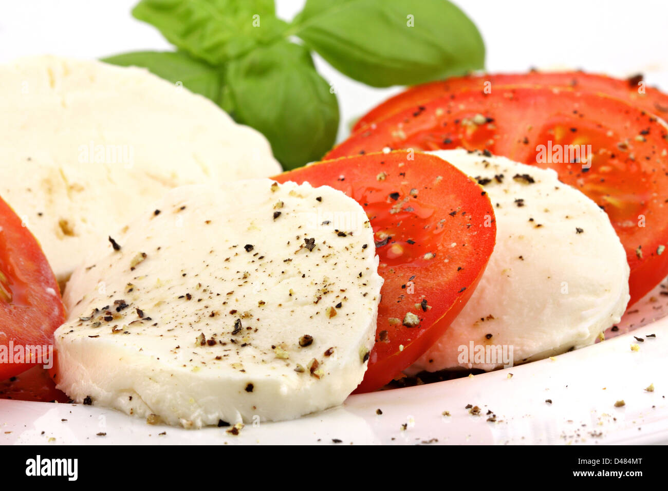 Mozzarella und Tomaten Scheiben mit Pfeffer und Basiliken. Stockfoto