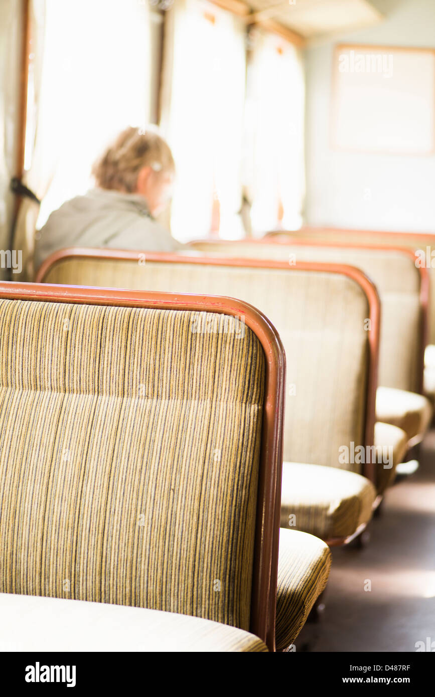 Einsame ältere Weibchen sitzen allein in einem Zug, unscharf. Stockfoto