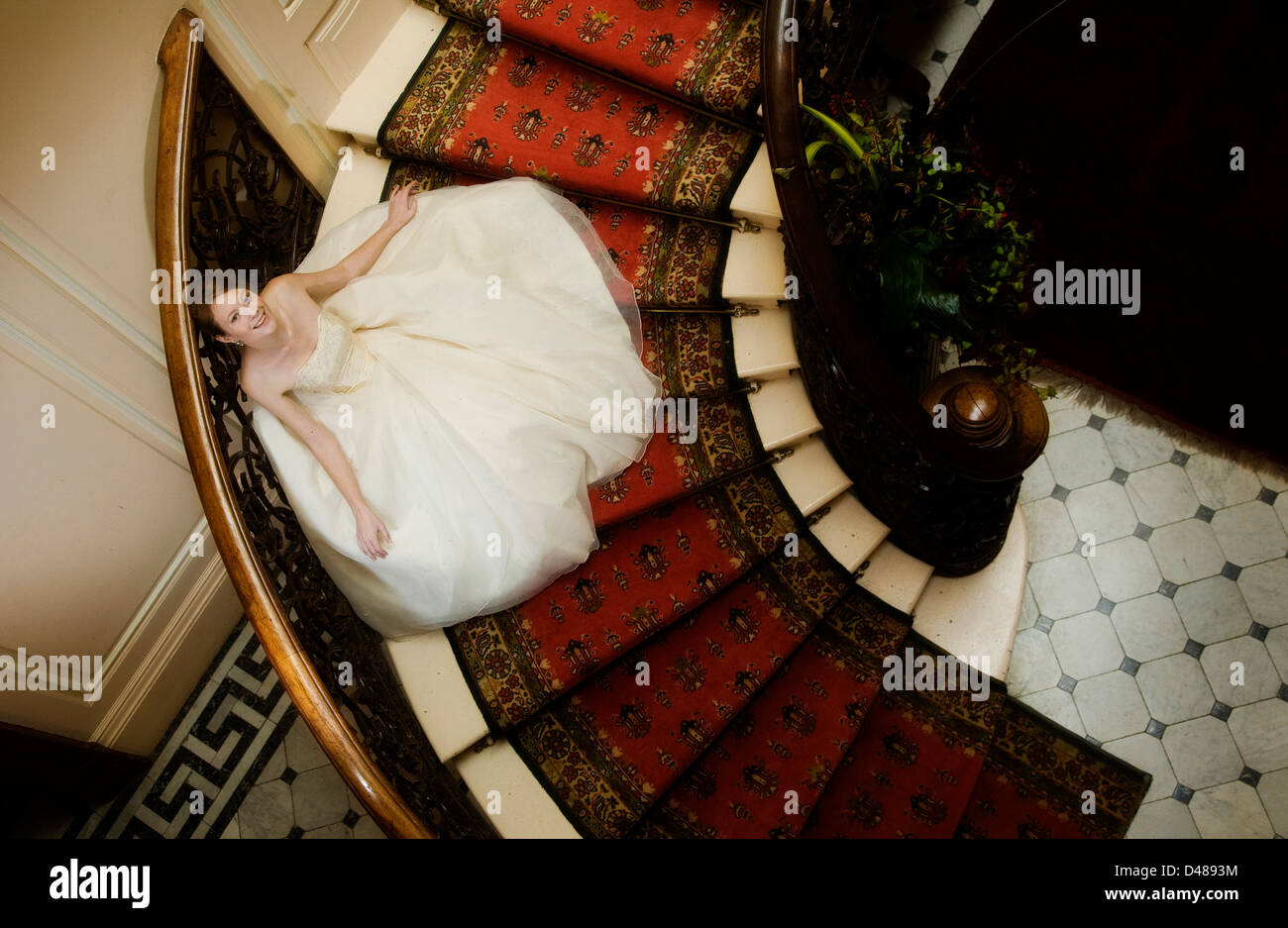 Braut auf verzierten Treppe mit voll mit Röckchen Creme trägerlosen Brautkleid von oben fotografiert Stockfoto