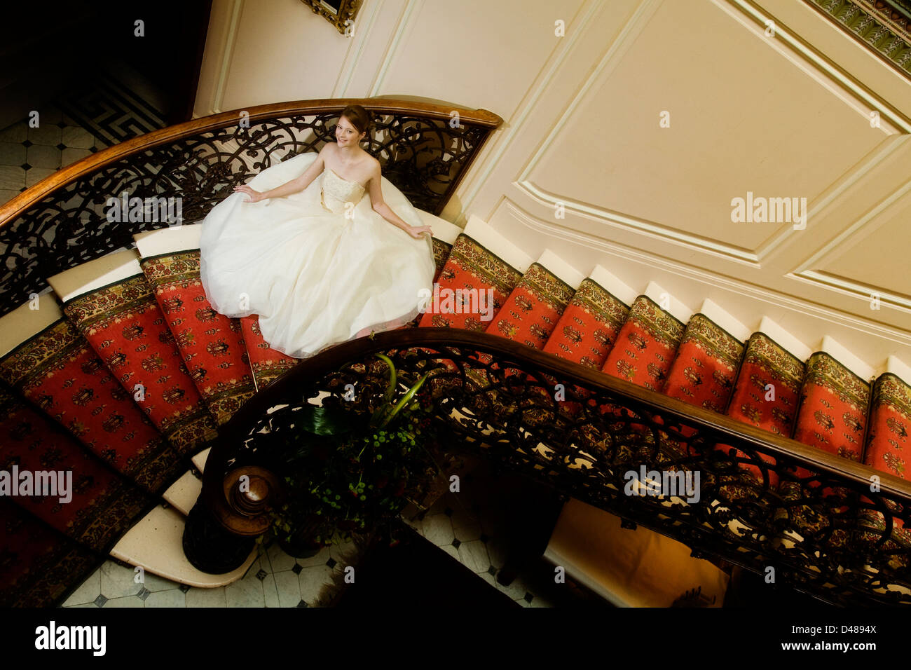 Braut auf verzierten Treppe mit voll mit Röckchen Creme trägerlosen Brautkleid von oben fotografiert Stockfoto