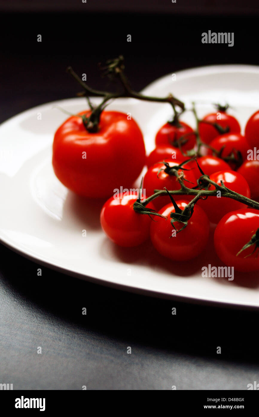 Schuss von frisch auf die Strauchtomaten auf einer herzförmigen Platte. Stockfoto