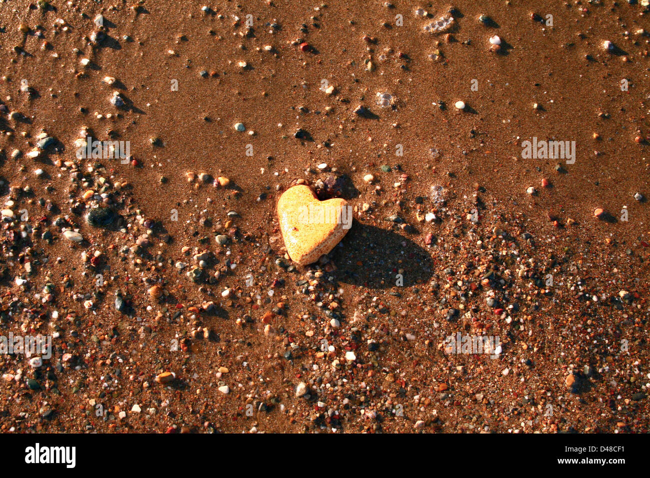 Eine herzförmige Stein am Ufer Meeres unter der Sonne Stockfoto