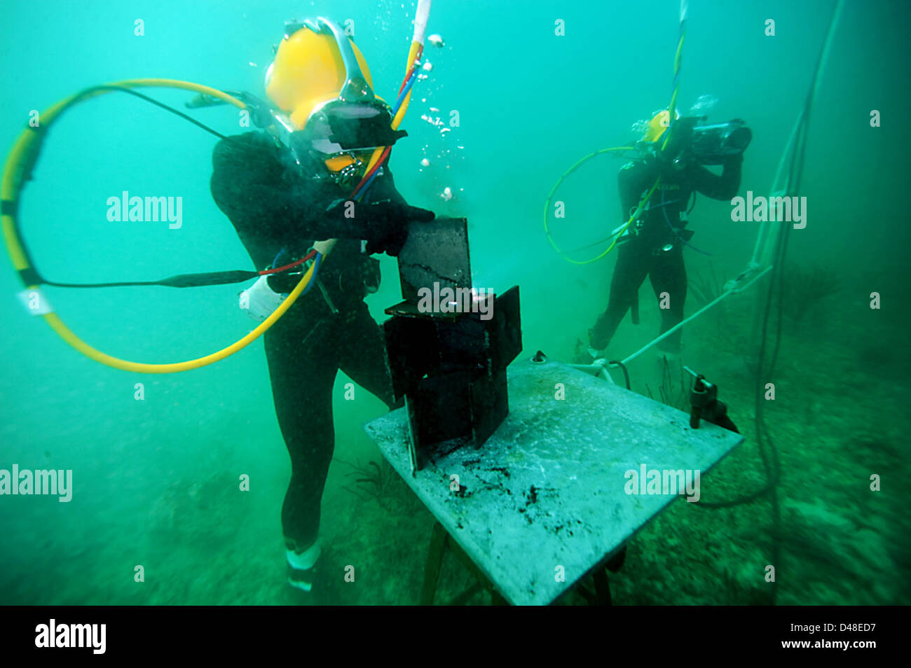 Ein Taucher der US Navy verwendet eine Unterwasser-Schweißbrenner für Reparaturen während einer Mission vor der Küste von Key West, Florida. Die Arbeit des Tauchers ist entscheidend für die Wartung und Reparatur von Ausrüstung in Meeresumgebungen. Stockfoto